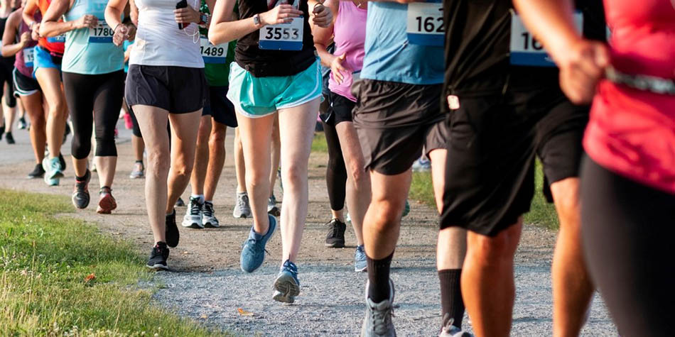 A group of runners with racing bibs jogs along a 5k trail.