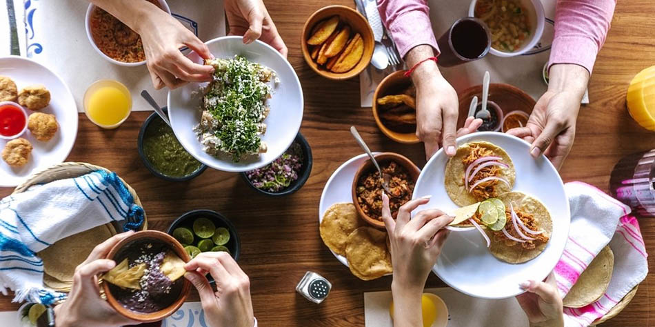 Hands reach for tacos across a table.