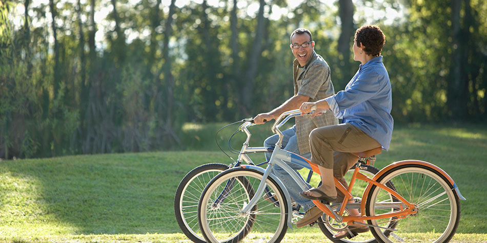 Two people ride bikes together on a sunny day